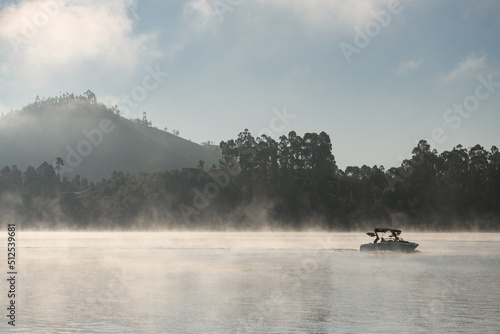 beautiful view of modern motorboat floating against the backdrop of a hill and trees