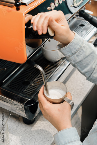 Barista making latte art in specialty coffee shop. Professional man making pouring stream milk with espressoProcess of preparing milk foam for cappuccino or latte, heating and whipping. 