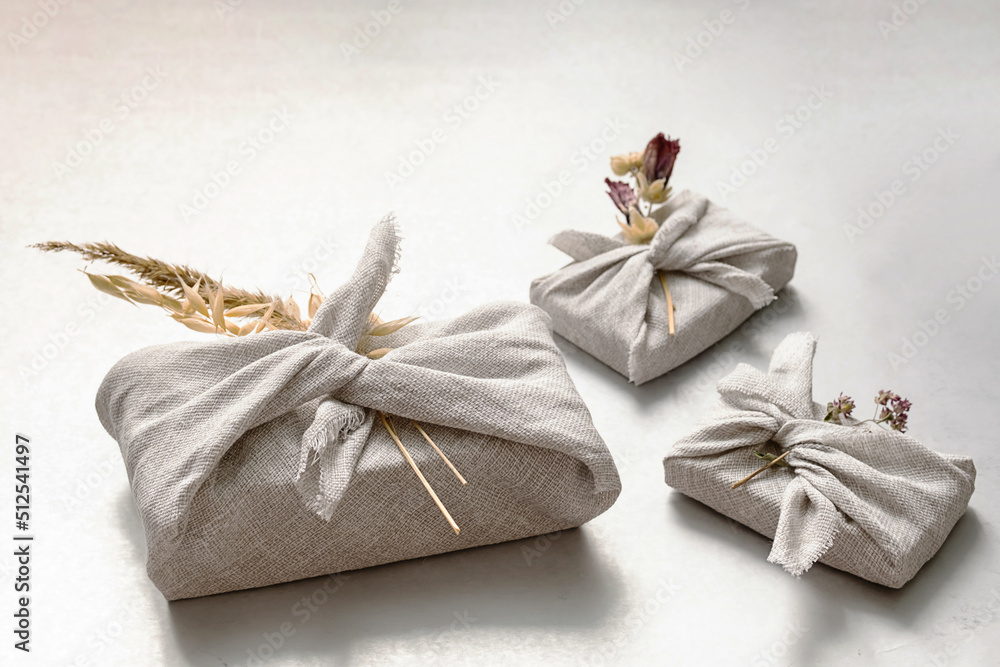 Presents wrapped in fabric and decorated dried flowers. Traditional Japanese gift wrapping furoshiki style. Zero waste holiday concept.