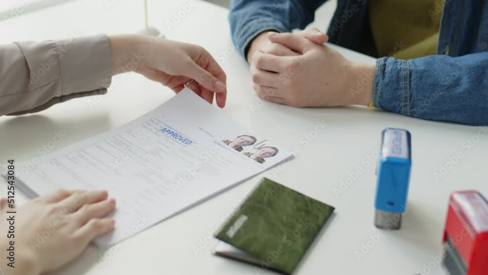 Tilt Up Shot Of Female Consular Officer Putting Approved Stamp On Application Form For Shengen tilt-up-shot-of-female-consular-officer-putting-approved-stamp-on-application-form-for-shengen