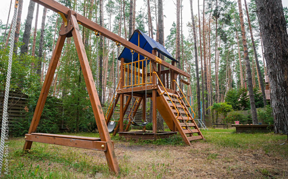 Children's wooden playground recreation area at forest. Wooden house with gazebo, lawn and concrete walkway in the forest. High quality photo Children's wooden playground recreation area at forest. Wooden house with gazebo, lawn and concrete walkway in the forest. High quality photo
