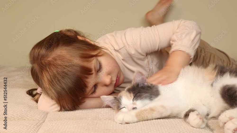 a little girl is lying on the sofa stroking a pet cat a little girl is lying on the sofa stroking a pet cat