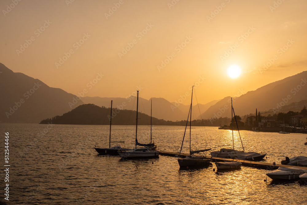 Tremezzina, the small harbor with boats, and the tip of Balbianello in the background, at sunset.