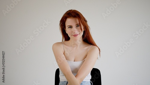 Beautiful young attractive woman sits on a chair, looking into the camera.