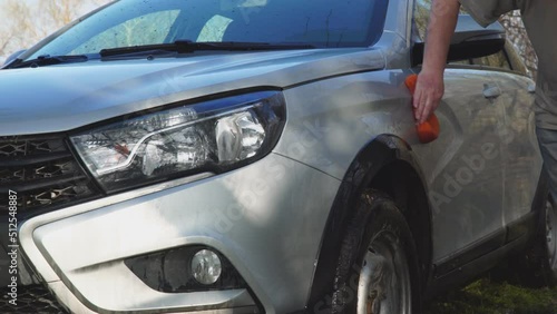 A man washes the car with a sponge and water from a bucket