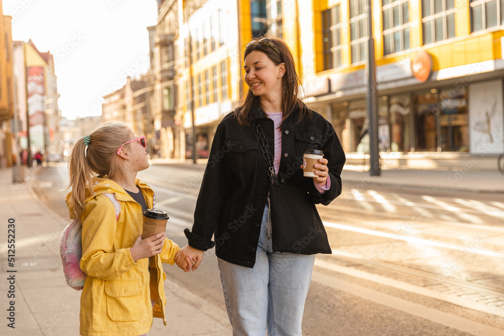 Fototapeta premium Close up view of mother and daughter walk with drinks and luffing
