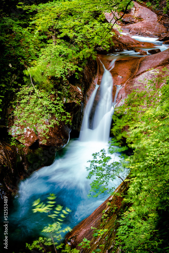 Beautiful Jungle waterfall in a tropical forest with rock and turquoise blue freshwater river. Summer season new leaves. Natural landscape background. Its name is Nishizawa Yamanashi, Japan