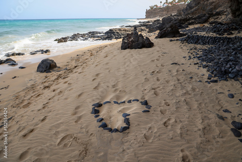 An einem Strand wurde ein Herz aus einzelnen Steinen gebildet. Steinherz am Strand.