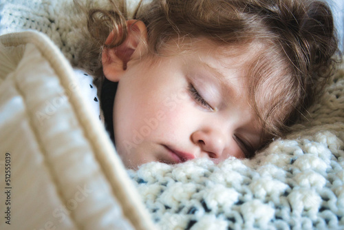 Close-up of a little girl sleeping peacefully wrapped up in a warm blanket