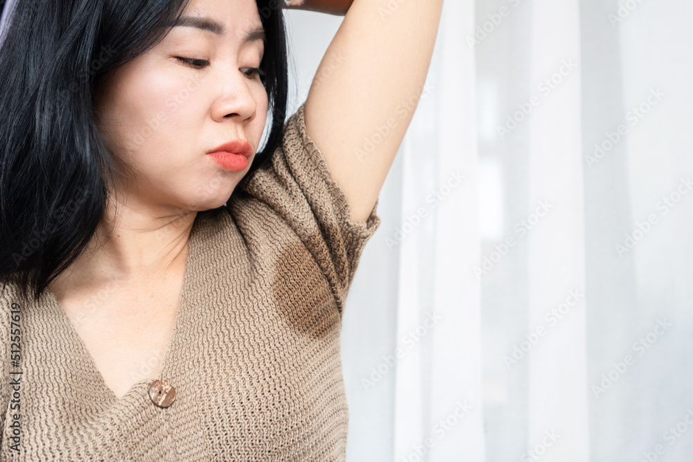 Asian woman having problem with sweat, smelly armpit showing her wet under arm Asian woman having problem with sweat, smelly armpit showing her wet under arm