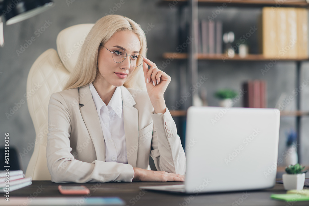 Photo of clever lawyer lady sitting chair hand touch eyeglasses read email workstation office indoors Photo of clever lawyer lady sitting chair hand touch eyeglasses read email workstation office indoors