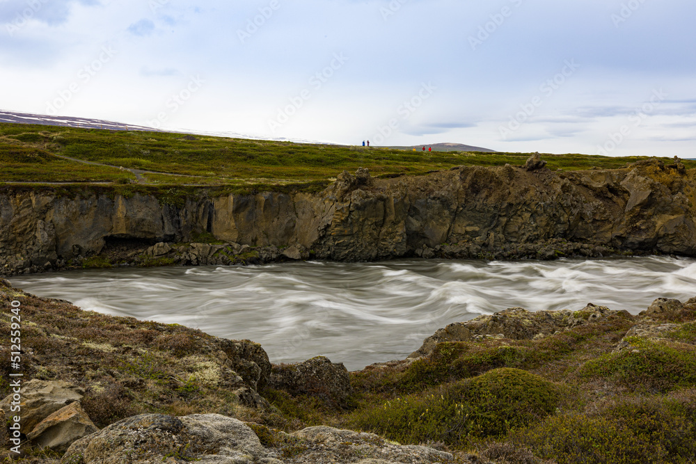 Force of the water running in Icelandic river flowing after Godafoss falls between volcanic rocks