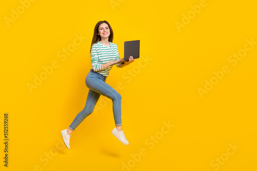 Full size profile side photo of charming good mood casual wear businesswoman browising in netbook isolated on yellow color background