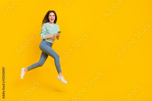 Fototapeta Naklejka Na Ścianę i Meble -  Full body image of cute cheerful girl chatting in phone receive many likes on her photo isolated on yellow color background