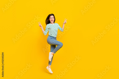 Full size photo of cheerful overjoyed female jumping showing v-sign say hello hi isolated on yellow color background