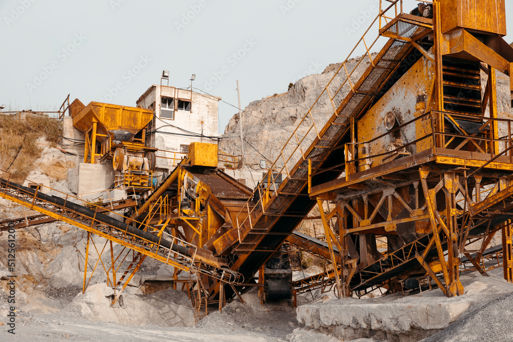 Quarry machines and piles of gravel over blue sky. Stone crushing and screening plant Quarry machines and piles of gravel over blue sky. Stone crushing and screening plant