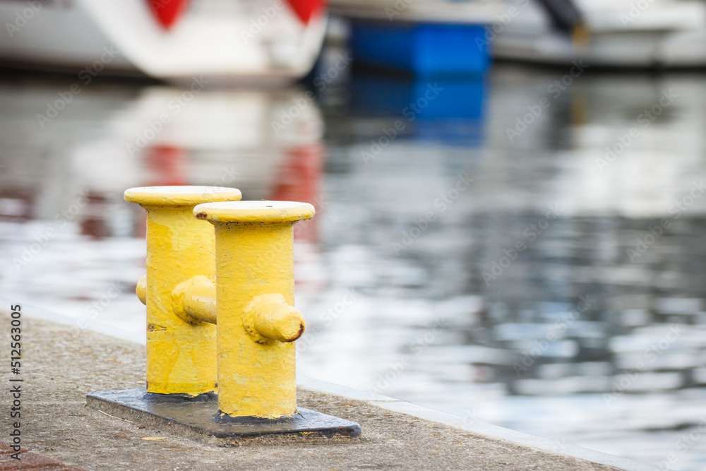 Yellow bollards on wharf using for anchorage of yachts. Detail of sailboat. Transportation Yellow bollards on wharf using for anchorage of yachts. Detail of sailboat. Transportation