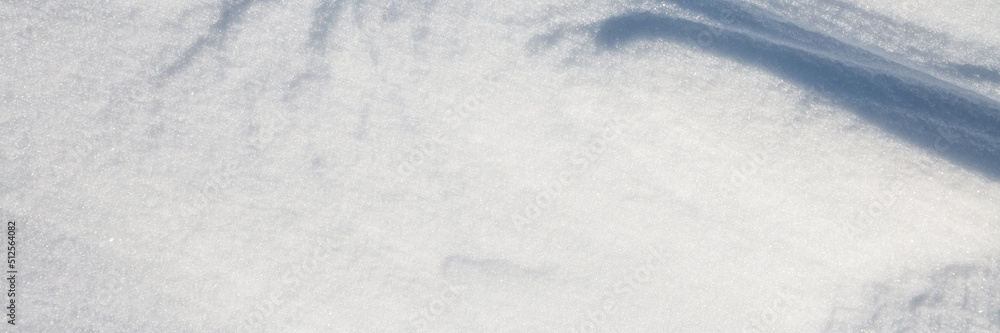 Obraz premium Beautiful winter background with snowy ground. Natural snow texture. Wind sculpted patterns on snow surface. Wide panoramic texture for background and design.