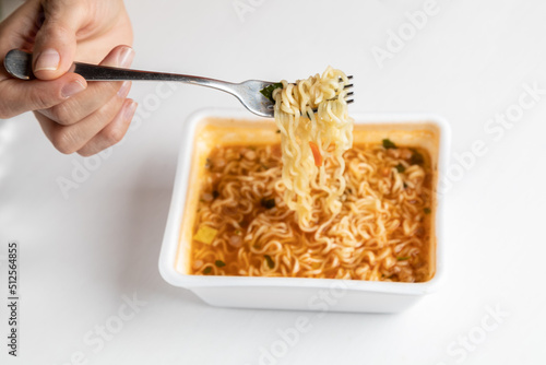 A woman eats instant noodles. Hot noodles on a fork.. White background