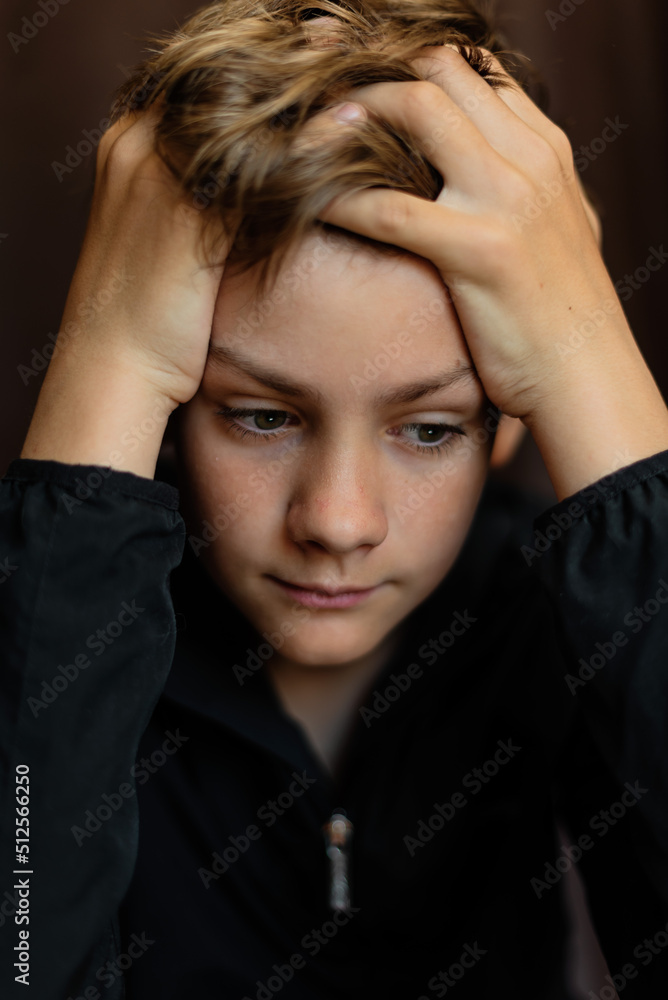 Portrait of blonde teenage boy on dark background outdoor. Low key close up shot of a young teen boy, adolescence. Selective focus. Loneliness, sadness, adolescent anxiety, emotional Portrait of blonde teenage boy on dark background outdoor. Low key close up shot of a young teen boy, adolescence. Selective focus. Loneliness, sadness, adolescent anxiety, emotional