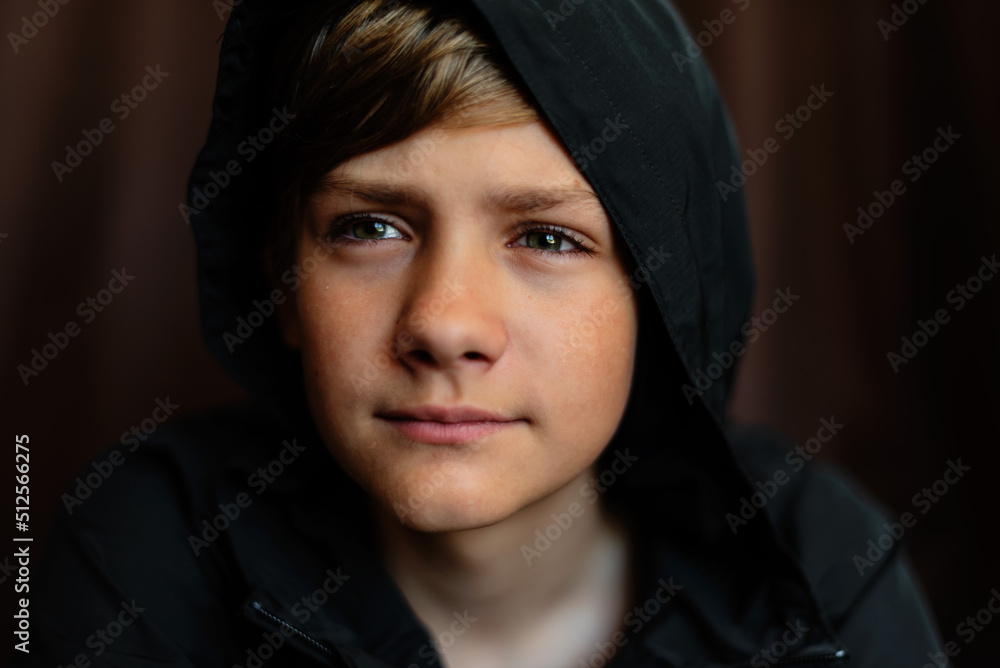 Portrait of blonde teenage boy on dark background outdoor. Low key close up shot of a young teen boy, adolescence. Selective focus. Loneliness, sadness, adolescent anxiety, emotional Portrait of blonde teenage boy on dark background outdoor. Low key close up shot of a young teen boy, adolescence. Selective focus. Loneliness, sadness, adolescent anxiety, emotional