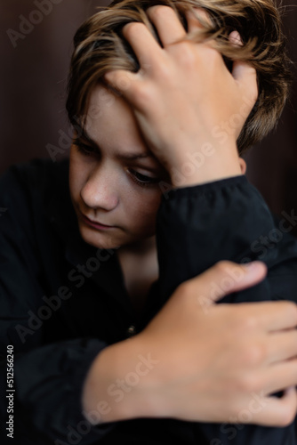 Portrait of blonde teenage boy on dark background outdoor. Low key close up shot of a young teen boy, adolescence. Selective focus. Loneliness, sadness, adolescent anxiety, emotional