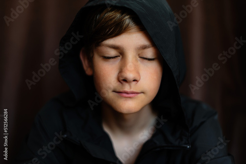 Portrait of blonde teenage boy on dark background outdoor. Low key close up shot of a young teen boy, adolescence. Selective focus. Loneliness, emotional, joy, happiness