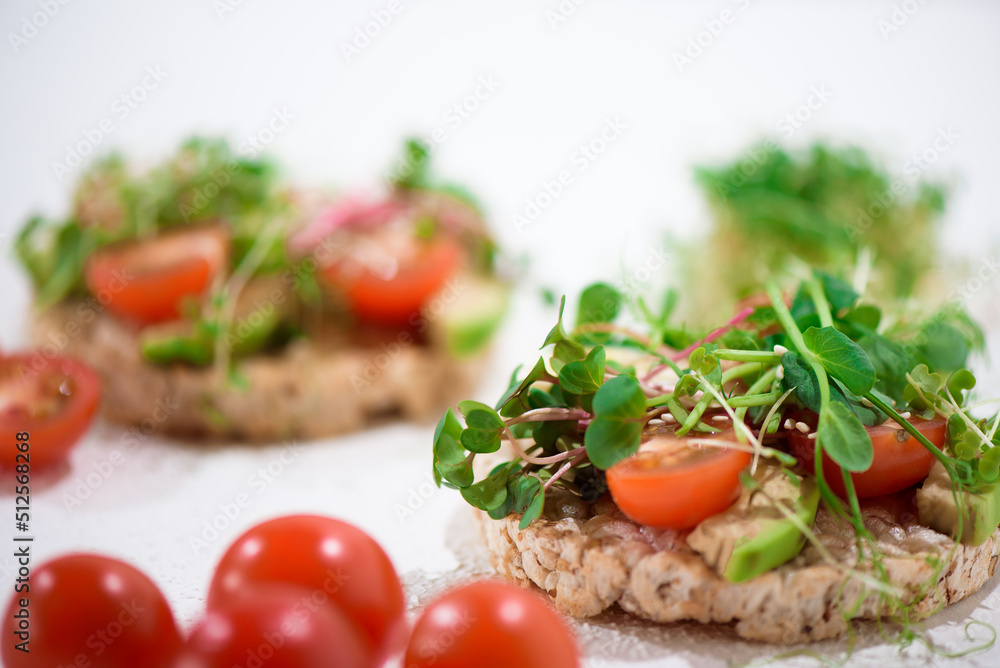Bright vegan tomato and avocado snacks. Sandwiches with tomato, microgreen and baby spinach. Bright vegan tomato and avocado snacks. Sandwiches with tomato, microgreen and baby spinach.