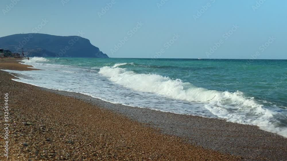 Small waves break on the pebbly beach as people frolic in the water Small waves break on the pebbly beach as people frolic in the water