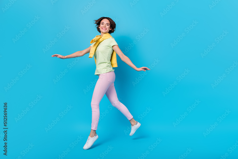 Obraz premium Full length profile photo of sweet millennial brunette lady run wear t-shirt trousers footwear isolated on blue background