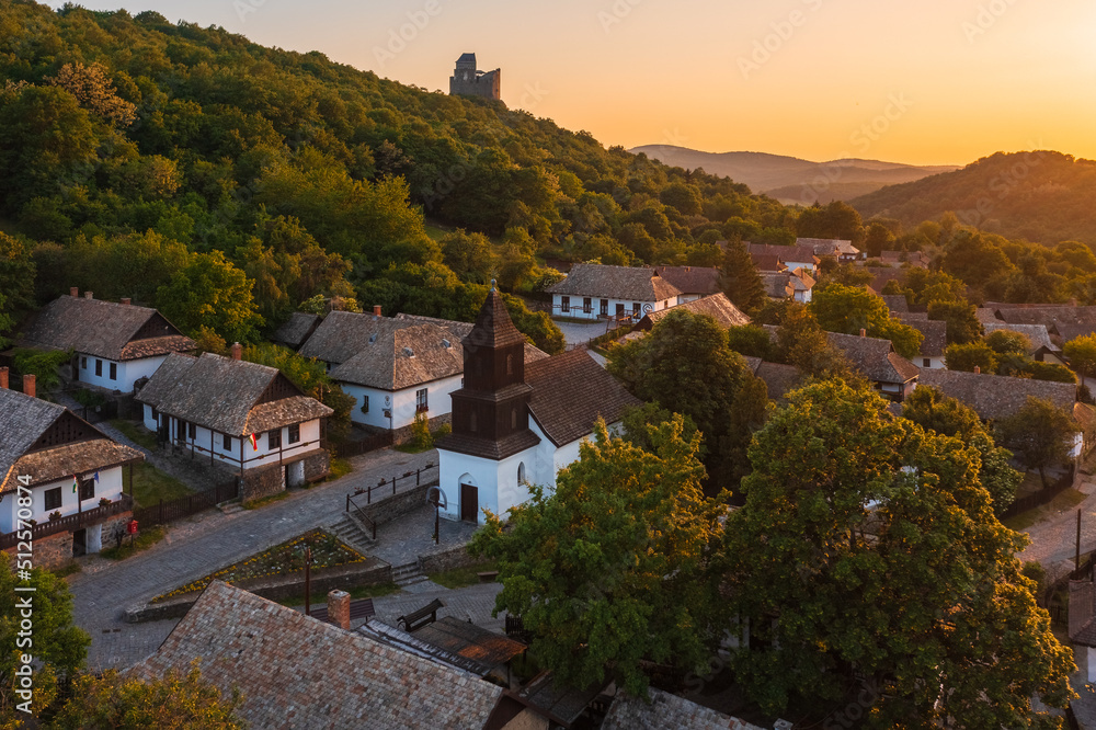 Aerial view about a tiny village named Hollókő with spectacular summer sunset over Cserhát mountains. Famous tourist destination, Unesco world heritage site.