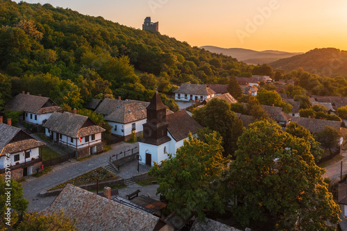 Aerial view about a tiny village named Hollókő with spectacular summer sunset over Cserhát mountains. Famous tourist destination, Unesco world heritage site. photo