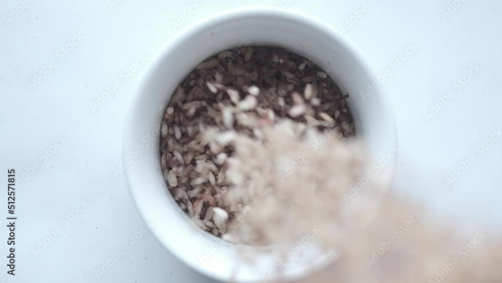 slow motion of raw brown rice pouring in a bowl on white slow motion of raw brown rice pouring in a bowl on white