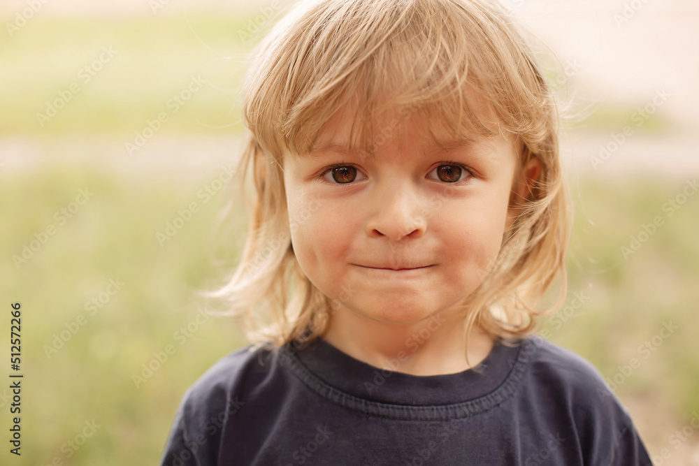 close-up portrait of the pensive face of a little blond boy on a green background summer street close-up portrait of the pensive face of a little blond boy on a green background summer street