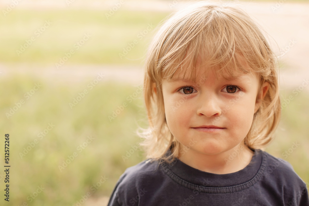 close-up portrait of the pensive face of a little blond boy on a green background summer street close-up portrait of the pensive face of a little blond boy on a green background summer street