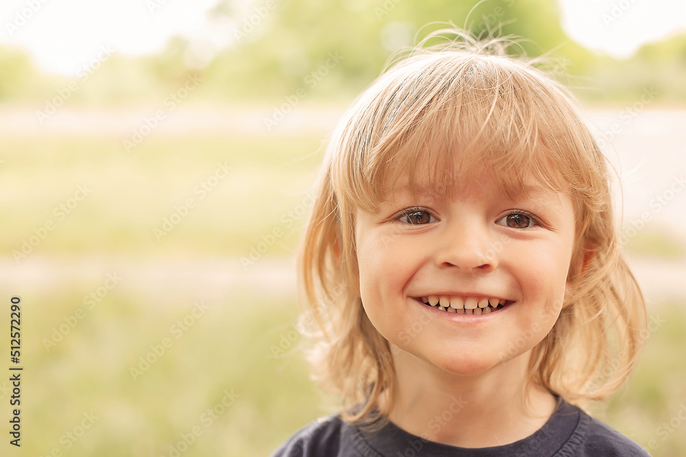 close-up portrait of the happy face of a little blond boy on a green background summer street close-up portrait of the happy face of a little blond boy on a green background summer street