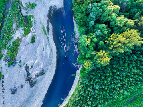 Fototapeta Naklejka Na Ścianę i Meble -  A rocky river in the middle of a forest. Aerial view of tranquil river reflecting sky, amid lush green landscape, aerial view. Top view of a mountain river in the forest.
