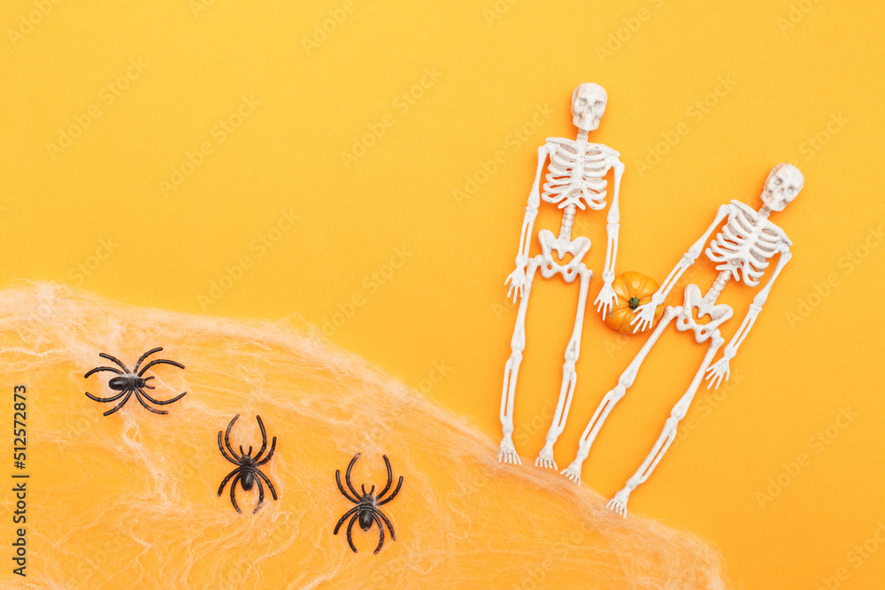 skeletons with pumpkin, spider web and black spiders on orange background. halloween concept