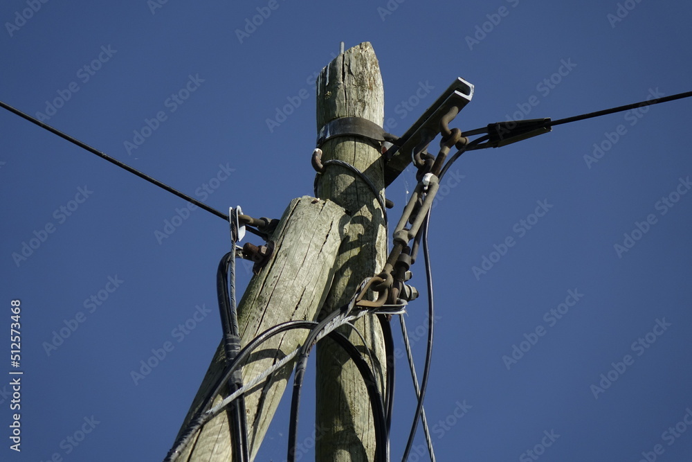 Wires and top of old wooden telegraph pole plus small cobbweb on the right side under a blue spring sky, concept: vintage, use: background, wallpaper, copy space (horizontal), Sehnde, Germany Wires and top of old wooden telegraph pole plus small cobbweb on the right side under a blue spring sky, concept: vintage, use: background, wallpaper, copy space (horizontal), Sehnde, Germany