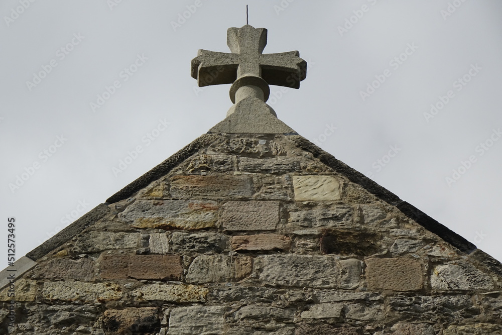 Yellow sandstone gable and stone cross of Protestant St. Nicolai church (low angle view) under a cloudy spring sky (horizontal), Sarstedt, Lower Saxony Germany Yellow sandstone gable and stone cross of Protestant St. Nicolai church (low angle view) under a cloudy spring sky (horizontal), Sarstedt, Lower Saxony Germany