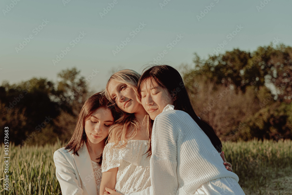 Fototapeta premium THREE HAPPY GIRLS EMBRACED IN THE COUNTRYSIDE. 