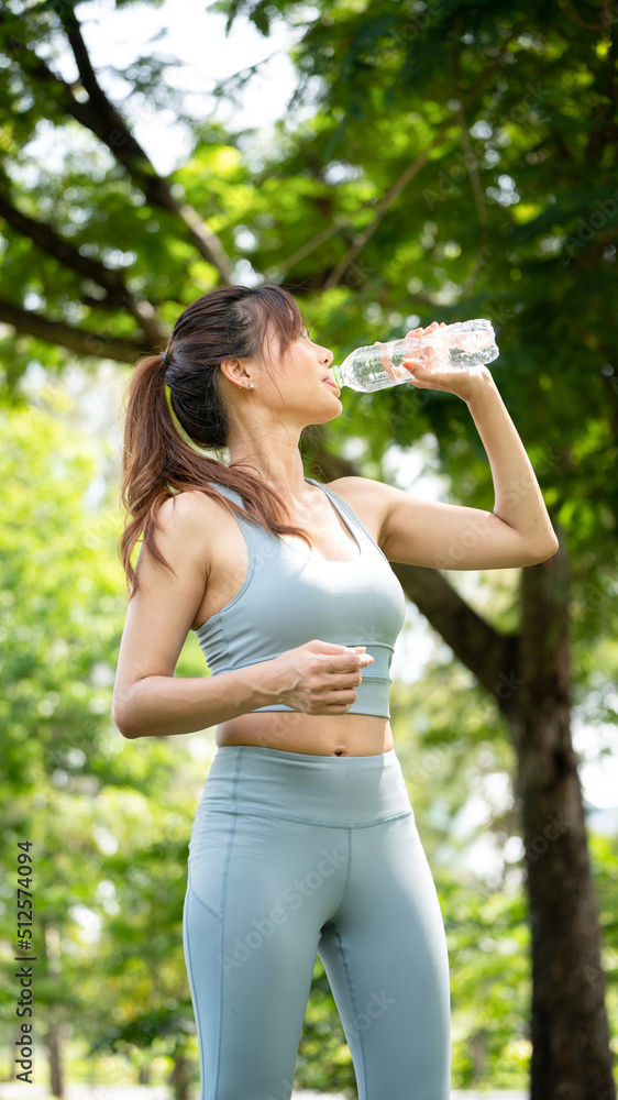 Fitness woman drinking water, Young thirsty woman drinking water from a bottle in summer park, Sport woman drink water after exercise in city park Fitness woman drinking water, Young thirsty woman drinking water from a bottle in summer park, Sport woman drink water after exercise in city park