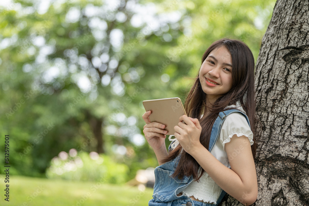 Thoughtful smile woman in park using smart digital tablet, Portrait of a young charming business woman checking online Business work on her smart tablet or labtop outdoors in the park on soft green Thoughtful smile woman in park using smart digital tablet, Portrait of a young charming business woman checking online Business work on her smart tablet or labtop outdoors in the park on soft green