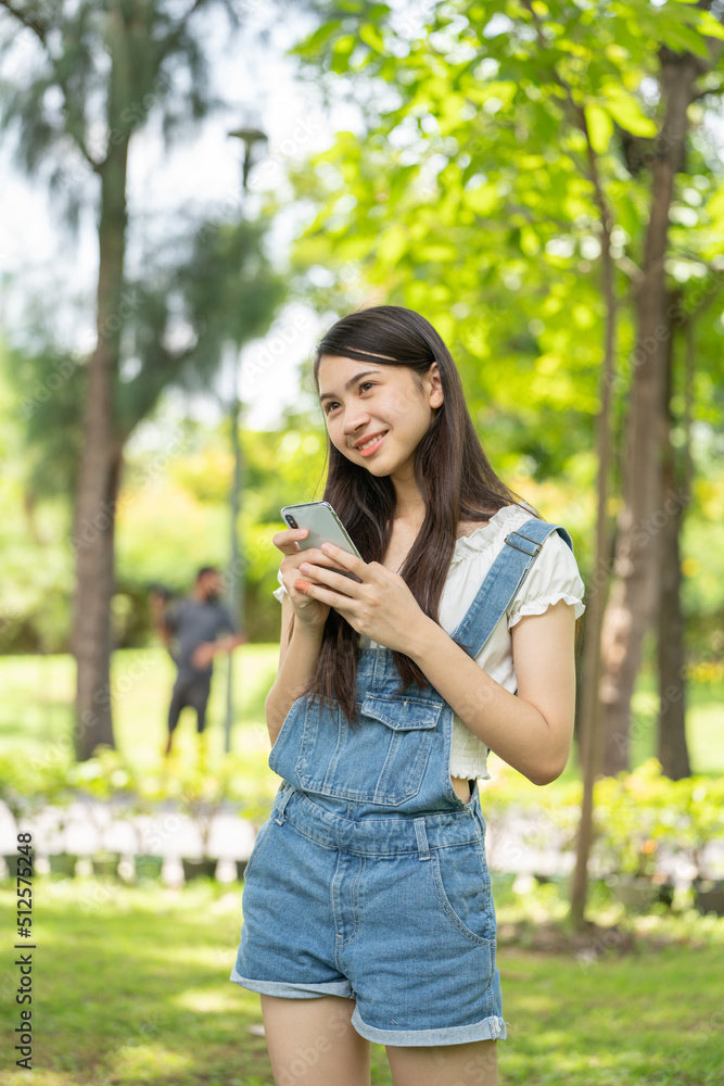 Thoughtful smile woman in park using smart phone, Portrait of a young charming business woman checking online Business work on her smart phone outdoors in the park on soft green back ground Thoughtful smile woman in park using smart phone, Portrait of a young charming business woman checking online Business work on her smart phone outdoors in the park on soft green back ground