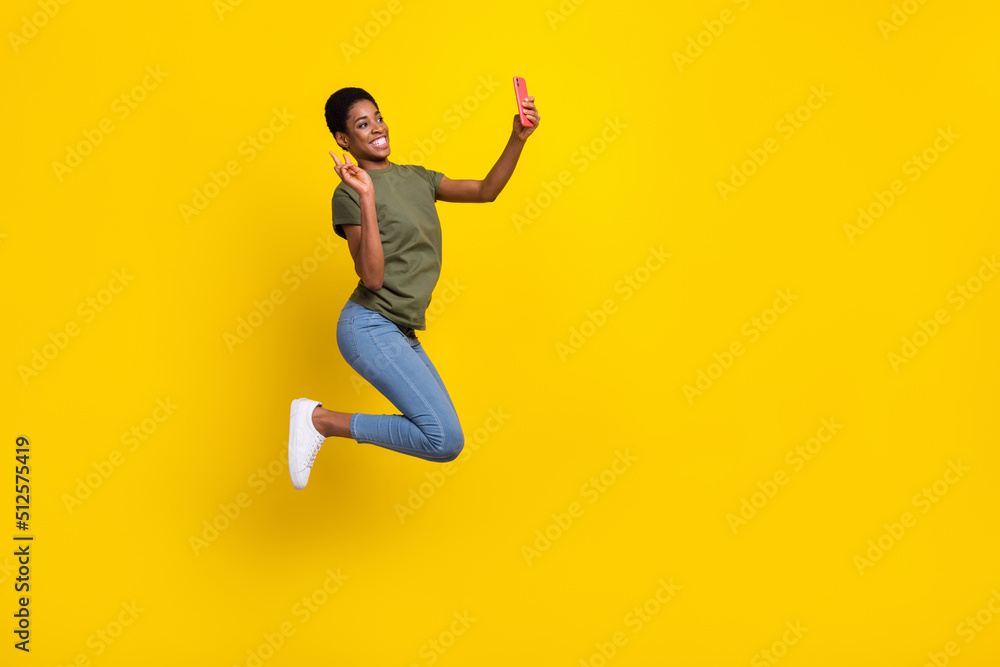 Full length portrait of crazy person blogger make selfie show v-sign jump isolated on yellow color background