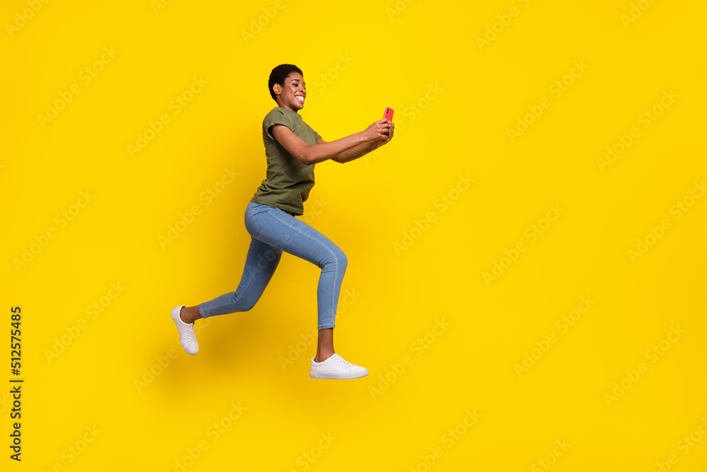 Full size portrait of crazy sporty person hold telephone jump rush fast isolated on yellow color background