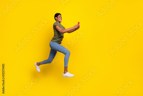 Full size portrait of crazy sporty person hold telephone jump rush fast isolated on yellow color background