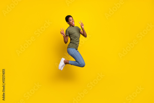 Full length portrait of friendly crazy person jump two hands demonstrate v-sign isolated on yellow color background