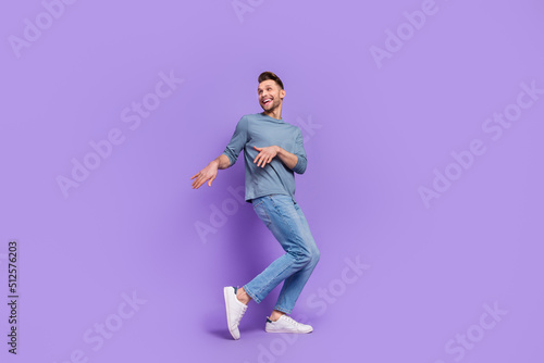 Photo of dreamy charming guy dressed grey shirt looking empty space dancing isolated purple color background