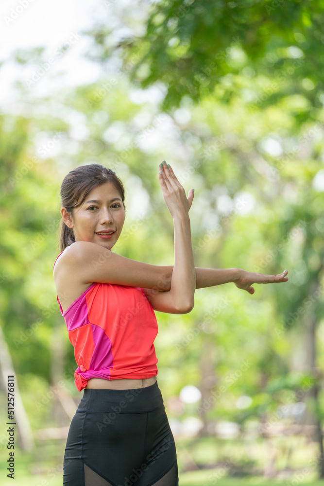 Healty Young female workout exercise before running or fitness training session in City Park. Healthy young woman warming up outdoors. She is stretching her arms at Garden park, Sports and activities Healty Young female workout exercise before running or fitness training session in City Park. Healthy young woman warming up outdoors. She is stretching her arms at Garden park, Sports and activities